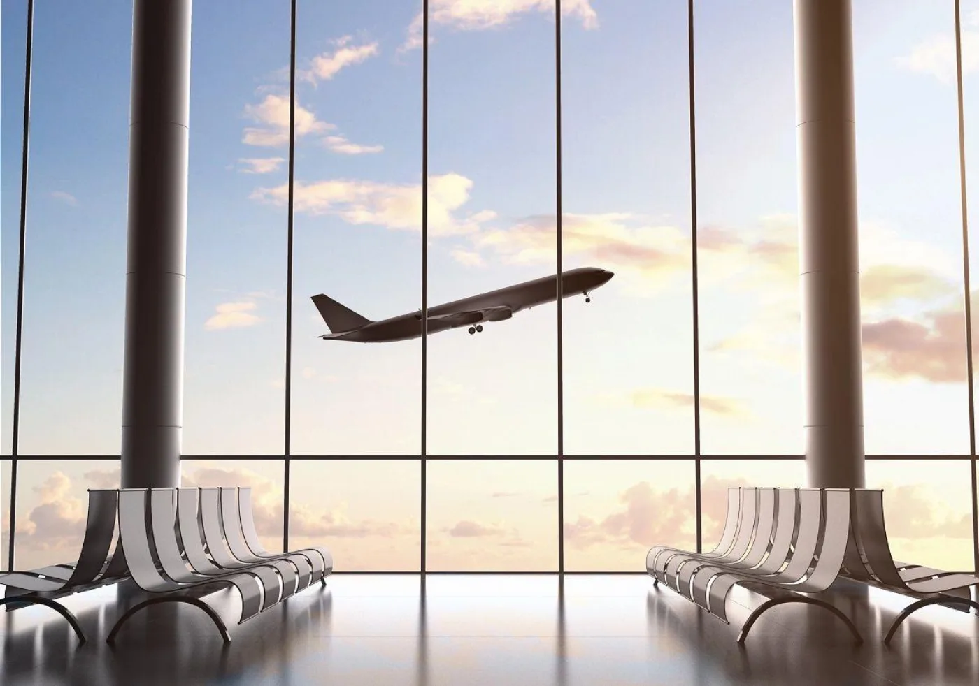 An airport terminal with benches and a plane departing at sunset